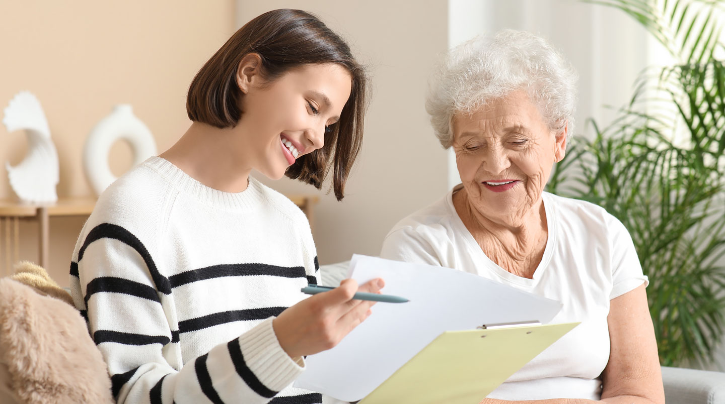 Gros plan sur des mains de personne senior avec une peau réaliste marquée par l'âge, tenant une brochure d'information sur un EHPAD, surface contemporaine propre en arrière-plan flouté